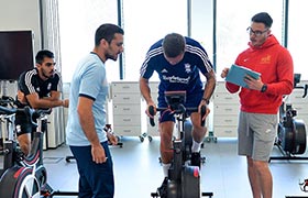 Student on an exercise bike with other students observing and taking notes
