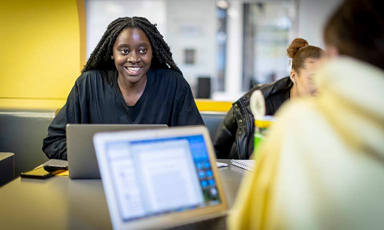 Female student smiling in front of laptop