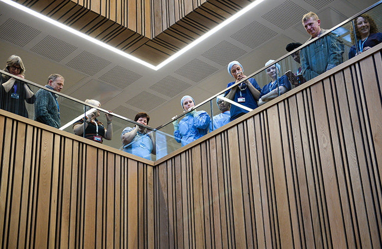 Staff and students looking down from a balcony in the Health and Life Sciences building watching the offical opening