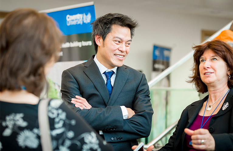 Three Coventry University staff members smiling and chatting