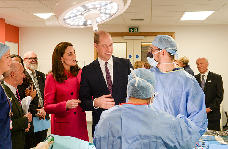 The Duke and Duchess of Cambridge in a mock operating theatre talking to two students dressed in operating scrubs and masks
