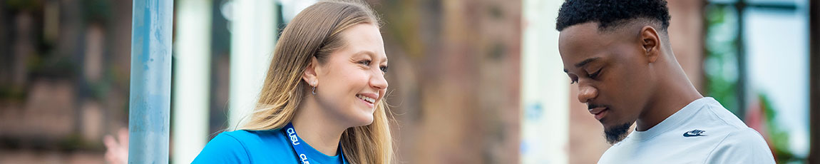 Smiling young lady talking to a student outdoors