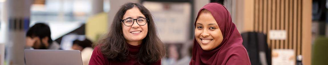 Two students smiling sitting in the courtyard