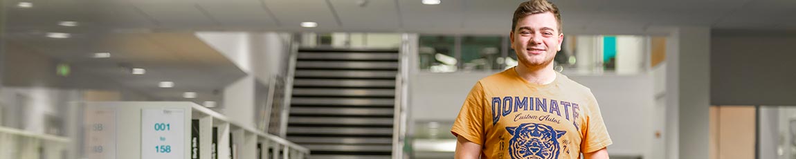 Mature student posing in a library building while wearing a yellow top