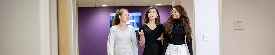 Three students walking and chatting in a corridor