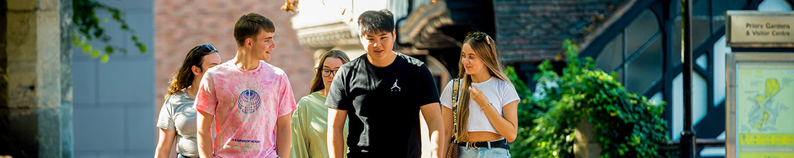 Four students talking and walking through Coventry