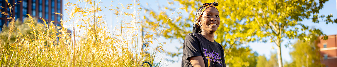 Student sat outside surrounded by green trees