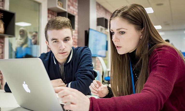 Female and male student looking at a MAC screen