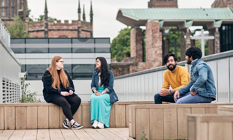 Four students sitting outside on a balcony