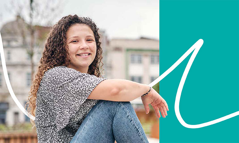 Student sitting and smiling with buildings in background