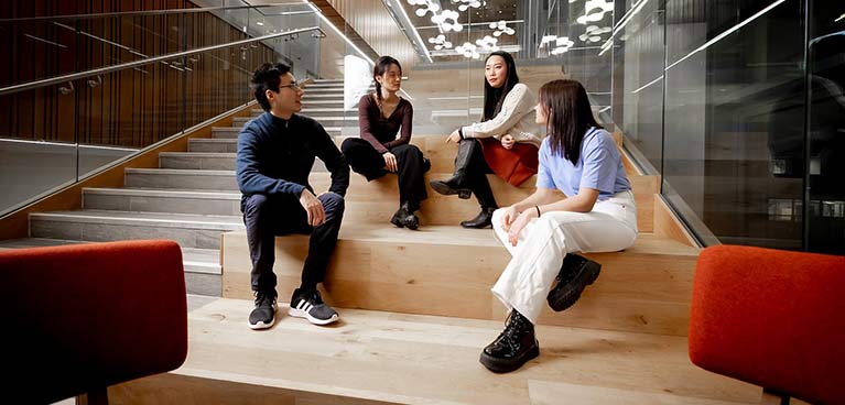 4 international students sitting on stairs chatting 