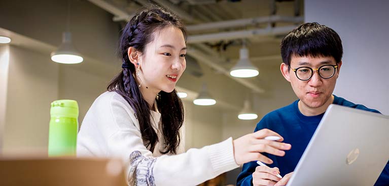 2 students chatting and looking at a laptop