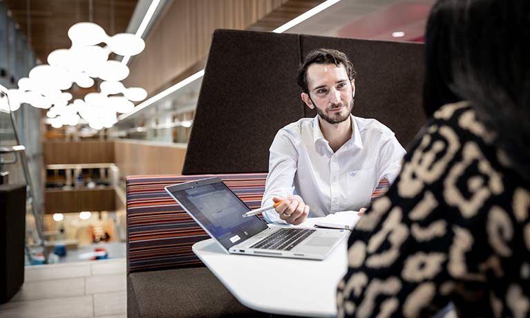 success coach and student looking in at a laptop in a student booth 