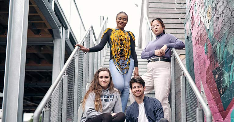 4 students on a staircase looking at the camera