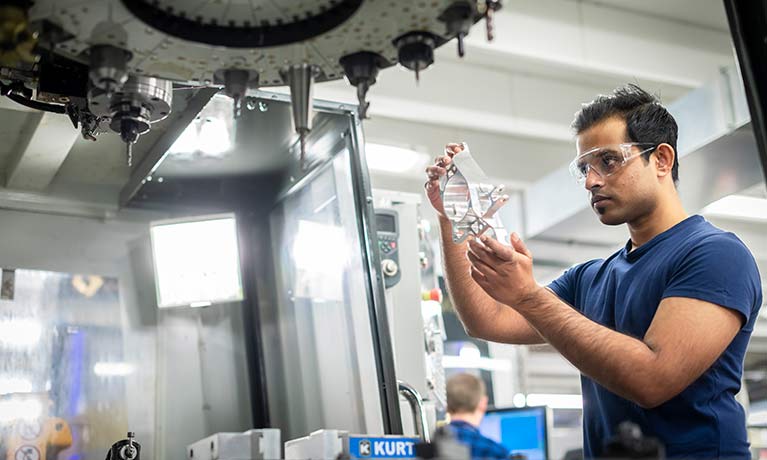 Male student  looking at piece of cut steel