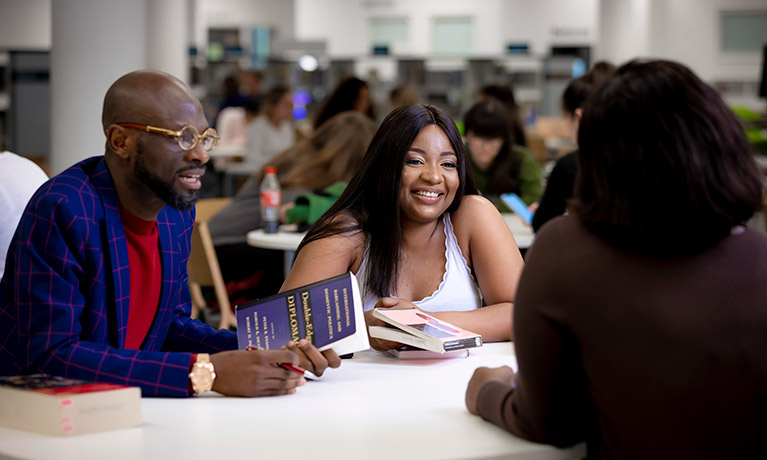 Two people with books talking across the table