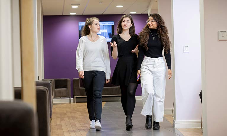 Three female students walking down at corridor