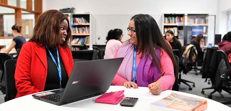 Two students at a desk talking