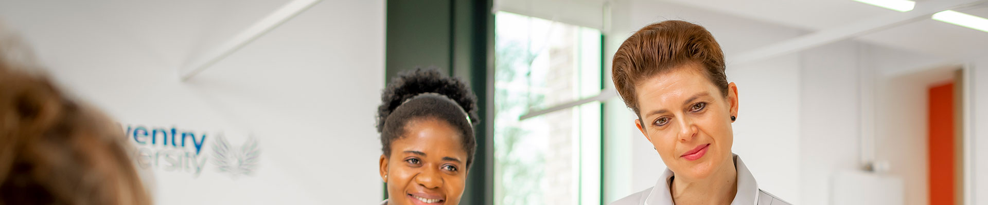 Student standing against a wall looking happy