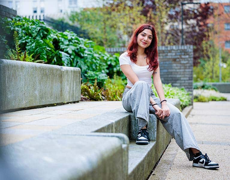 A student sat on some steps posing