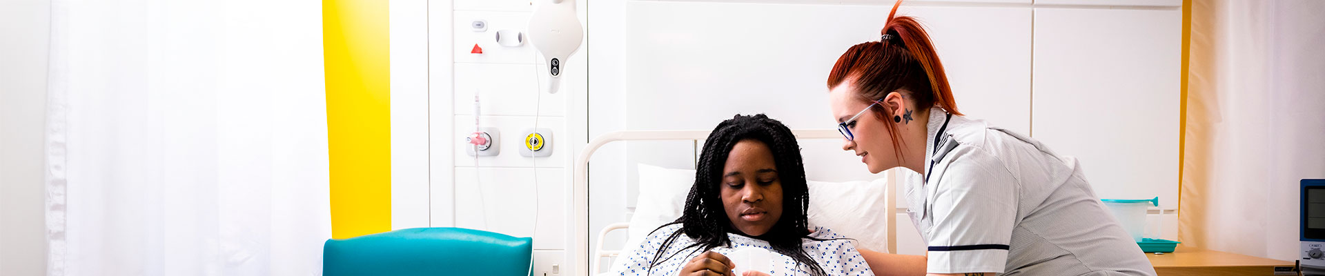 Student nurse caring for a patient in a hospital bed