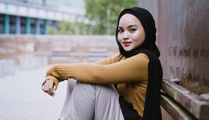 Female student sitting on the ground smiling