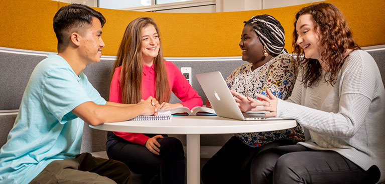 A group of students together chatting at a desk