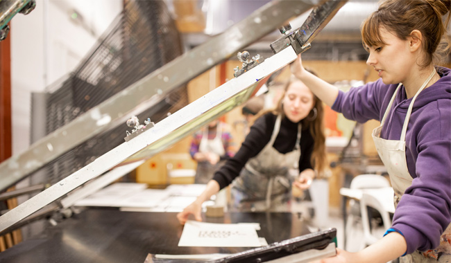 Two students screen printing in the arts studio.