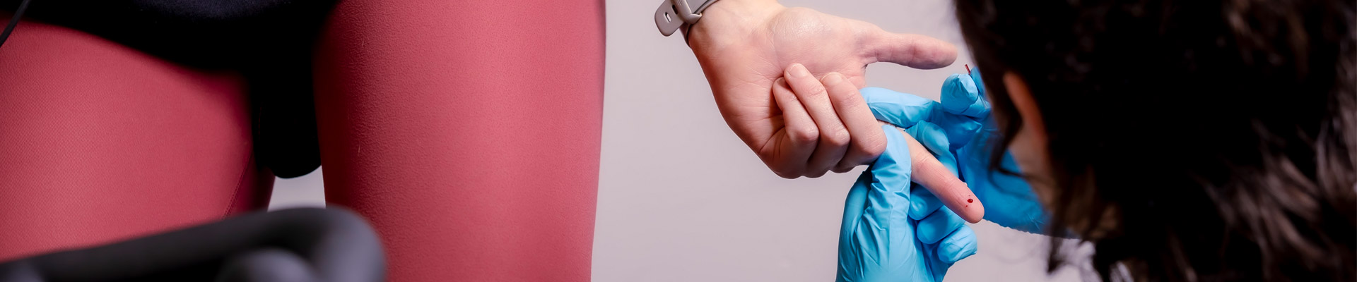A person on an exercise bike holding out their hand for a pinprick fingertip blood test