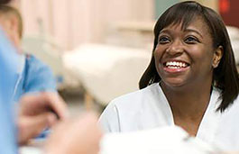 Nurse behind a desk smiling at another staff member