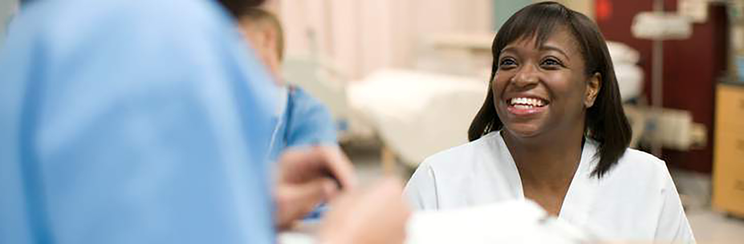 Nurse is seen smiling up at another healthcare worker who we can't see as they have their back to us