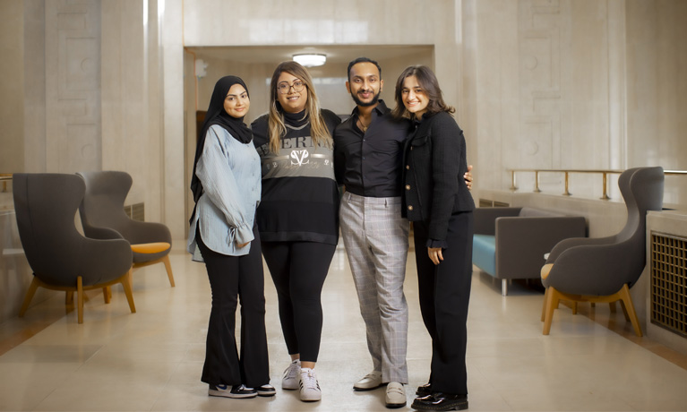 Four CU London students stood in the CUL Dagenham foyer smiling at the camera.