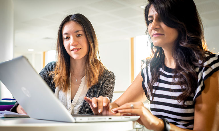 Two students working on a laptop