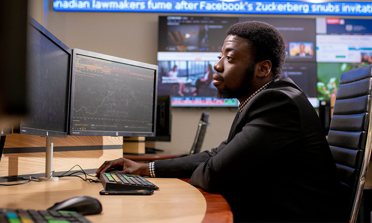 Student working on computer with dual monitors