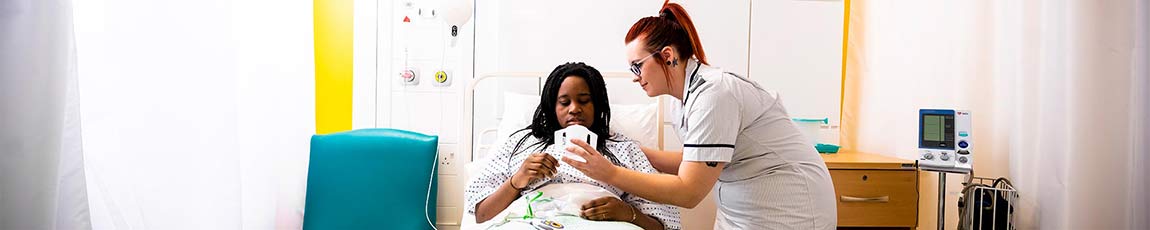 female nurse caring for a patient in a hospital bed