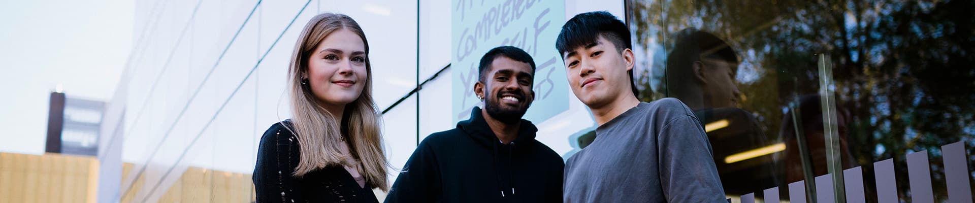 Students standing in front of the hub smiling for a photo