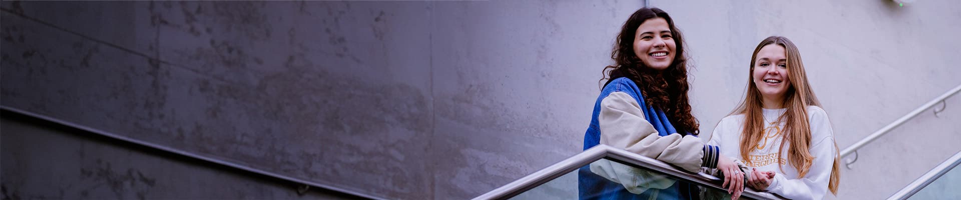Two students stood on a stair well talking to each other