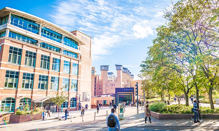 Students walking past the william morris building with a blue sky