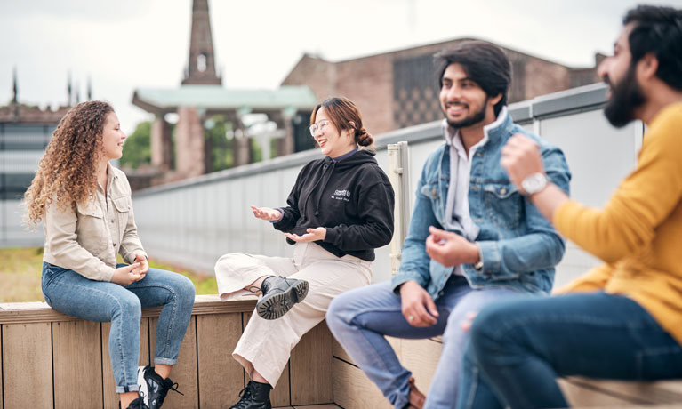 Students sitting on a bench on campus chatting
