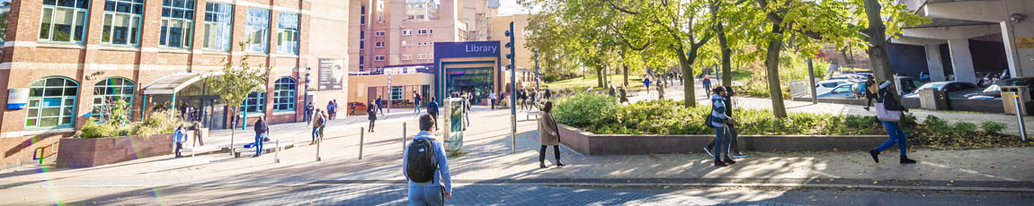 Students walking across campus with the library in the background.