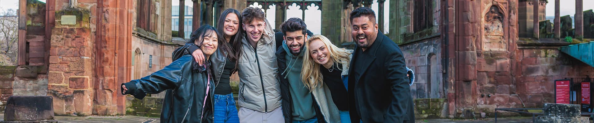 Group of students stood smiling in the cathedral ruins
