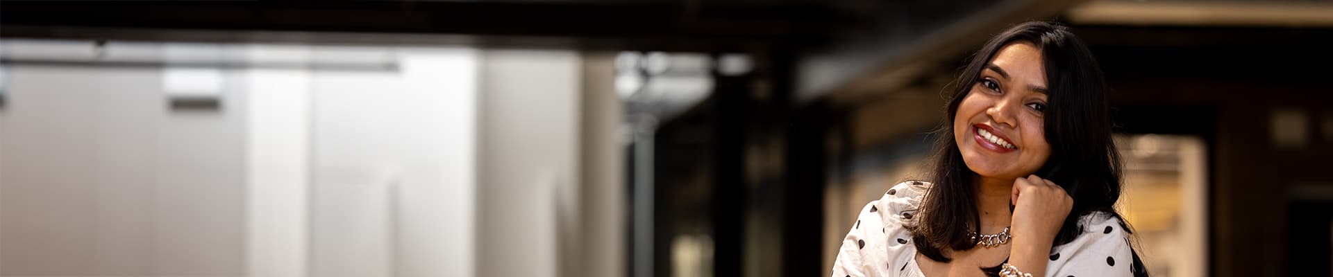 Female student stood smiling leaning on a wooden balcony