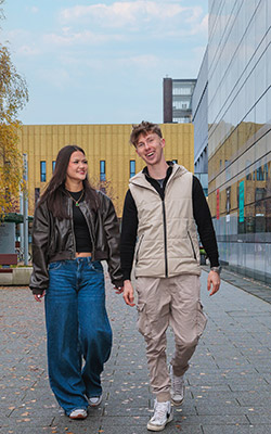 Two students talking whilst walking past The Hub