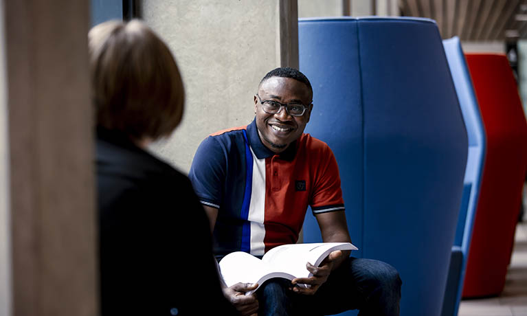 Student smiling and holding book.