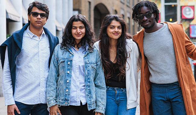 Four Coventry University London students smiling at camera standing on a London street 