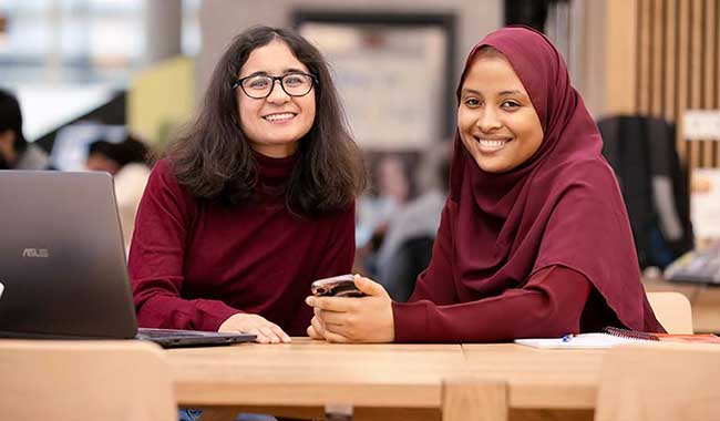 Two students sitting in a courtyard