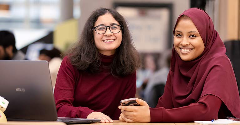 two female students smiling looking at the camera