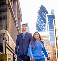 Two students walking with London buildings in the background