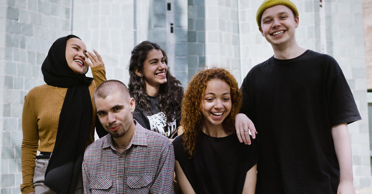 Four students smiling outside on campus.