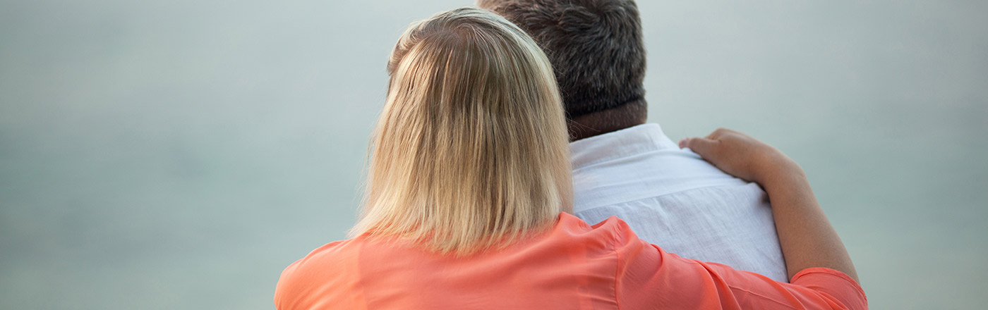 The back of a woman with her arm around a mans shoulder